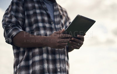 Buy stock photo Shot of an unrecognisable man using a digital tablet while working on a farm