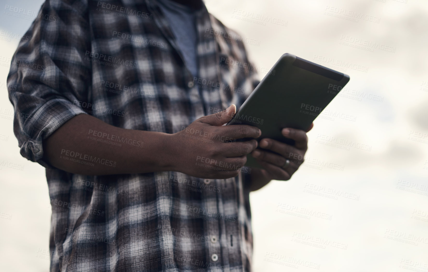 Buy stock photo Shot of an unrecognisable man using a digital tablet while working on a farm