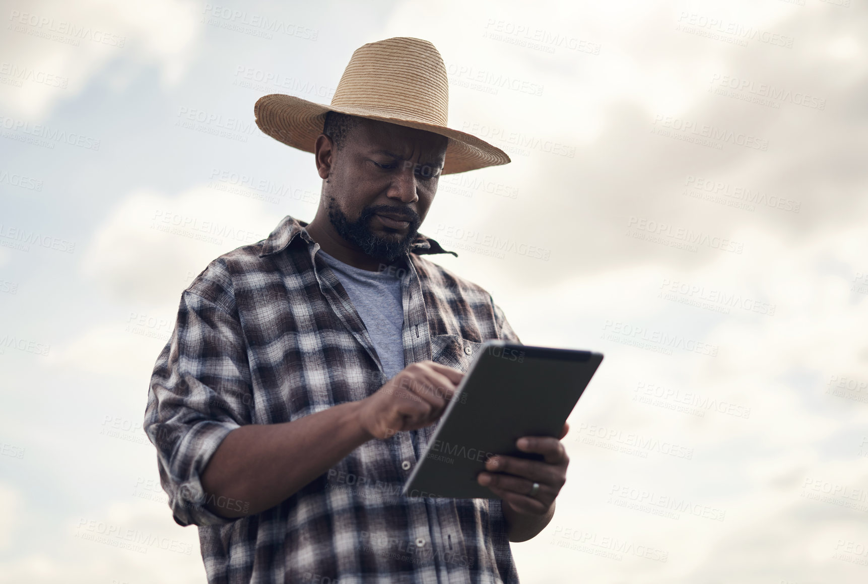 Buy stock photo Shot of a mature man using a digital tablet while working on a farm