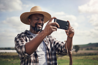 Buy stock photo Shot of a mature man using a smartphone to take pictures of a farm
