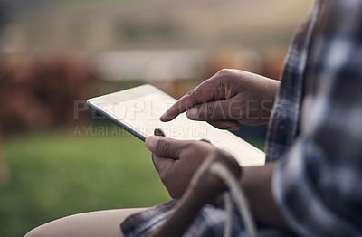 Buy stock photo Shot of an unrecognisable man using a digital tablet while working on a cow farm