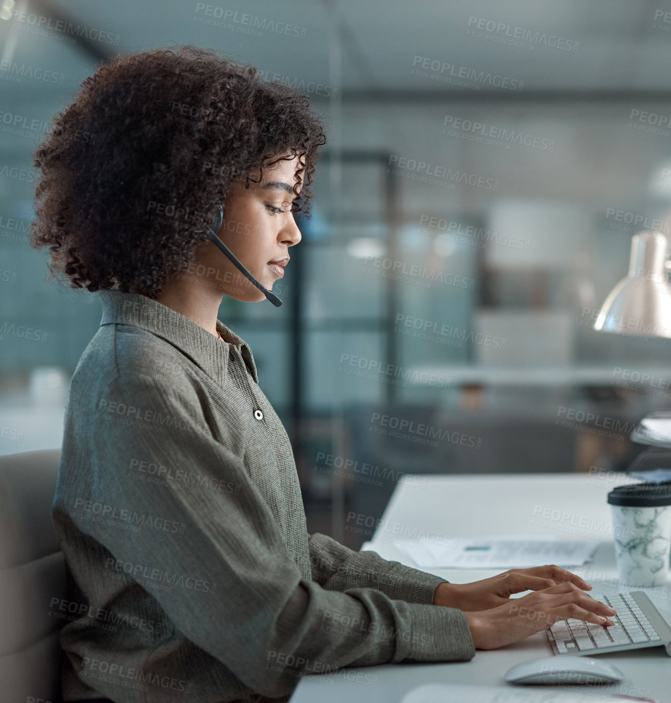 Buy stock photo Shot of a young female agent working in a call centre typing while on a call