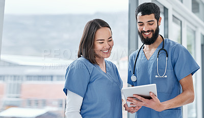 Buy stock photo Shot of two medical practitioners using a digital tablet together in a hospital