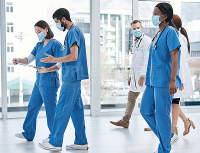 Buy stock photo Shot of a group of medical practitioners walking in a hospital