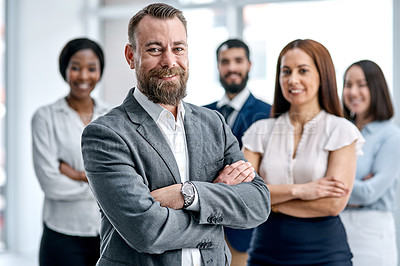 Buy stock photo Portrait of a businessman standing in an office with his colleagues in the background