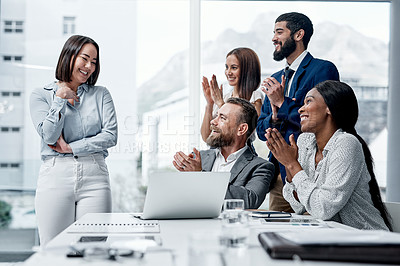 Buy stock photo Shot of a group of businesspeople applauding their colleague in an office