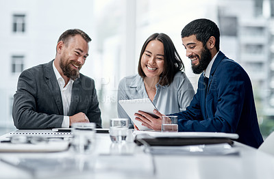 Buy stock photo Shot of a group of businesspeople working together on a digital tablet in an office