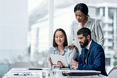 Buy stock photo Shot of a group of businesspeople working together on a digital tablet in an office