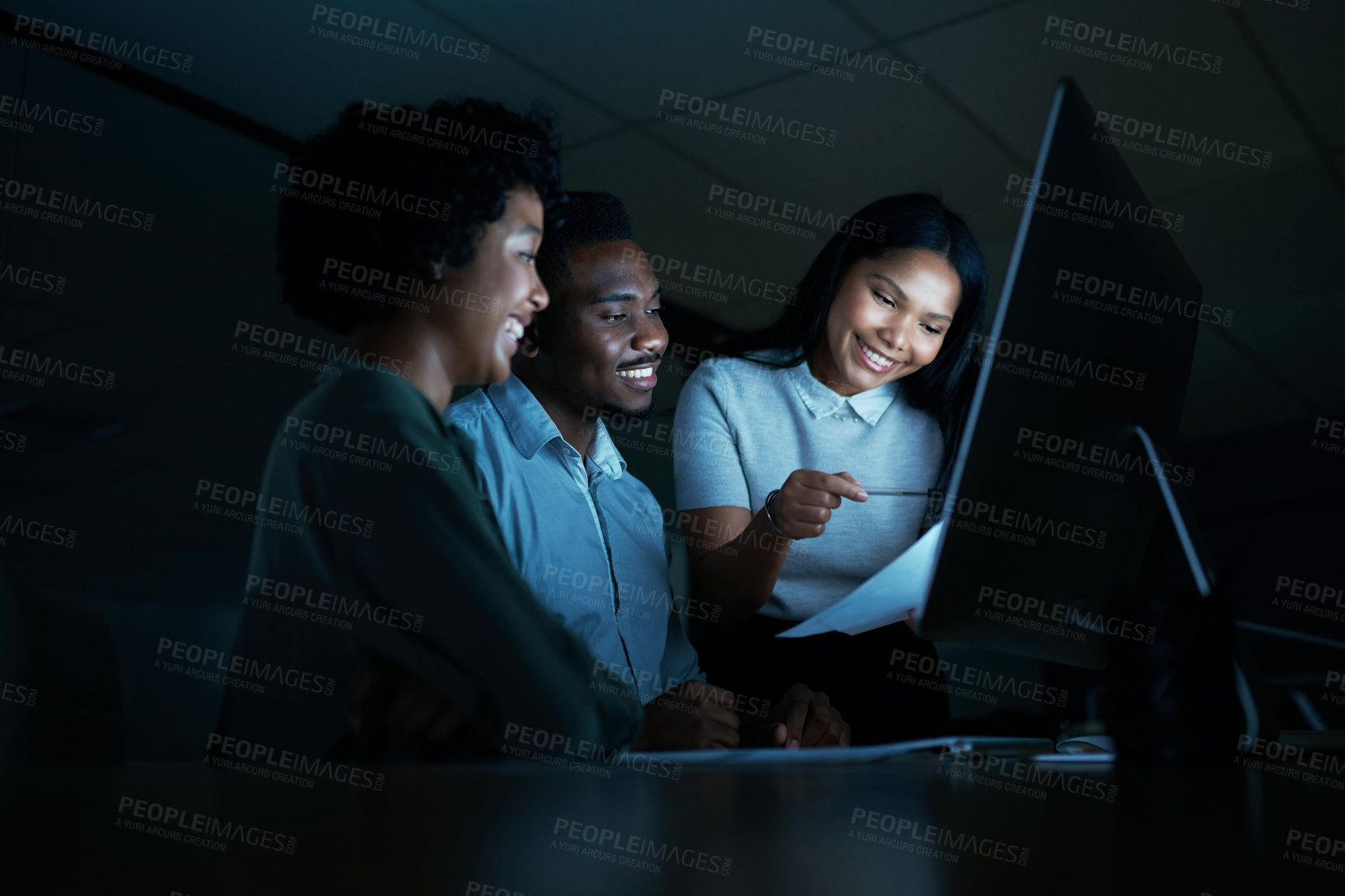 Buy stock photo Shot of a group of young businesspeople using a computer together during a late night at work