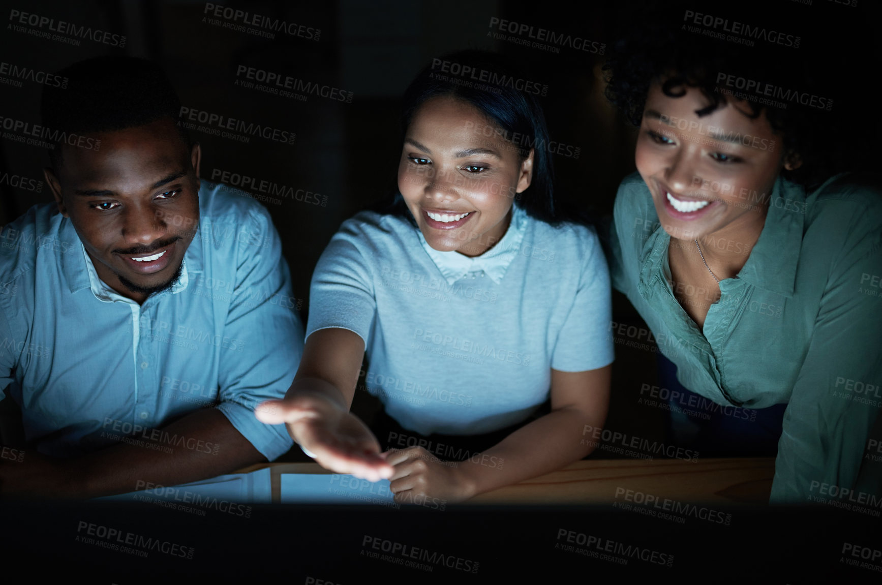 Buy stock photo Shot of a group of young businesspeople using a computer together during a late night at work