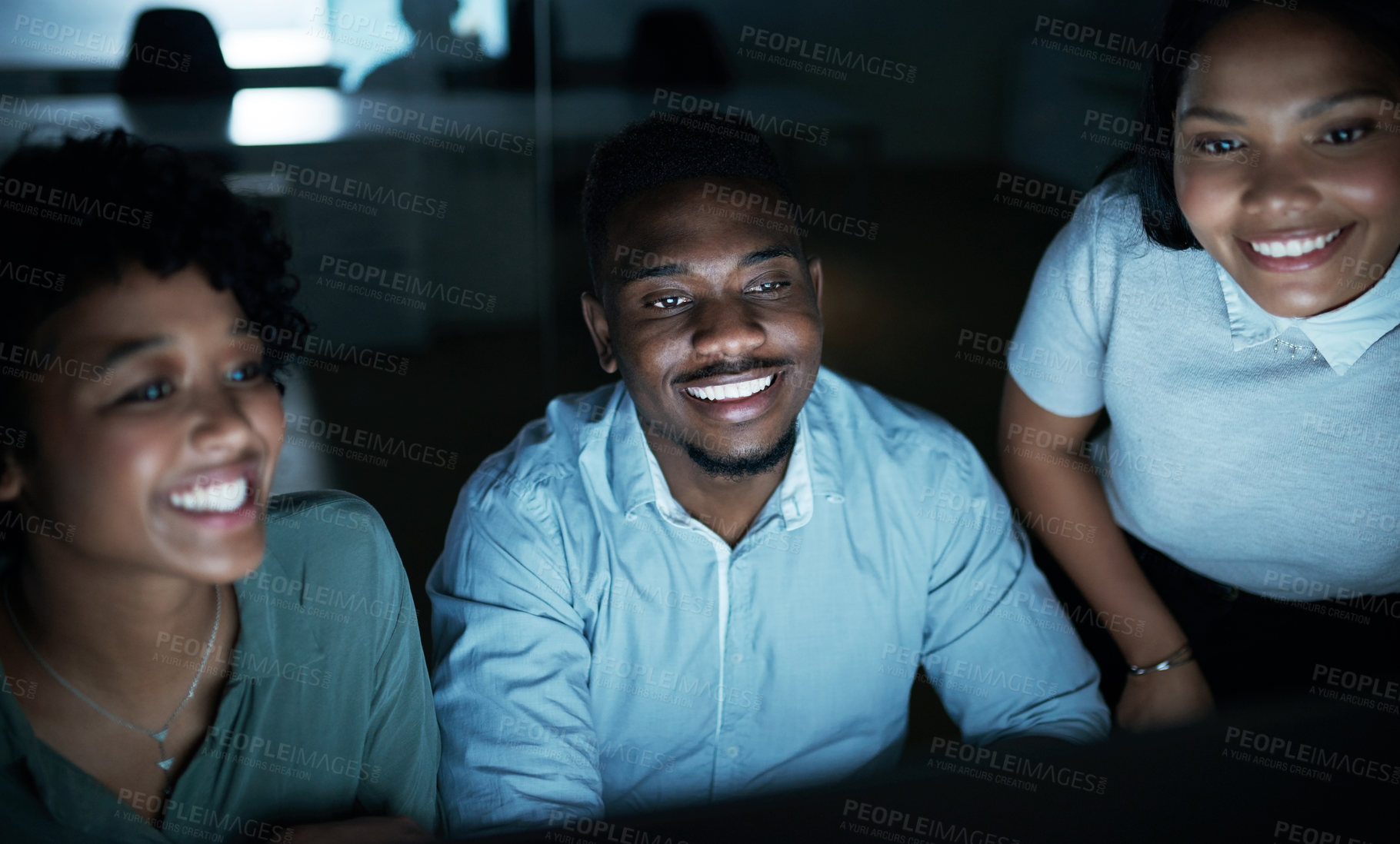 Buy stock photo Shot of a group of young businesspeople using a computer together during a late night at work