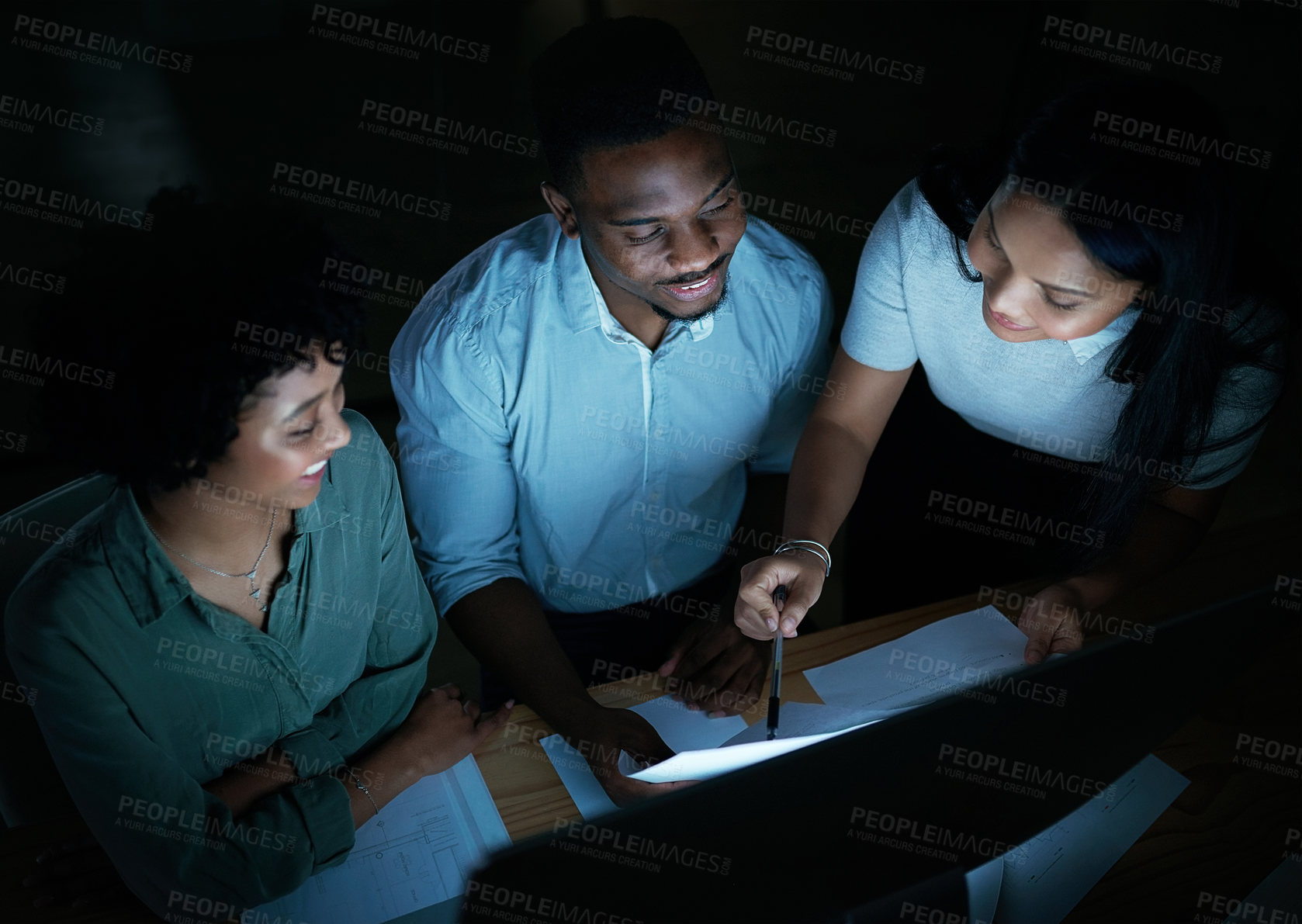 Buy stock photo Shot of a group of young businesspeople using a computer together during a late night at work