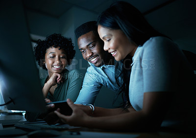 Buy stock photo Shot of a group of young businesspeople using a smartphone and computer together during a late night at work