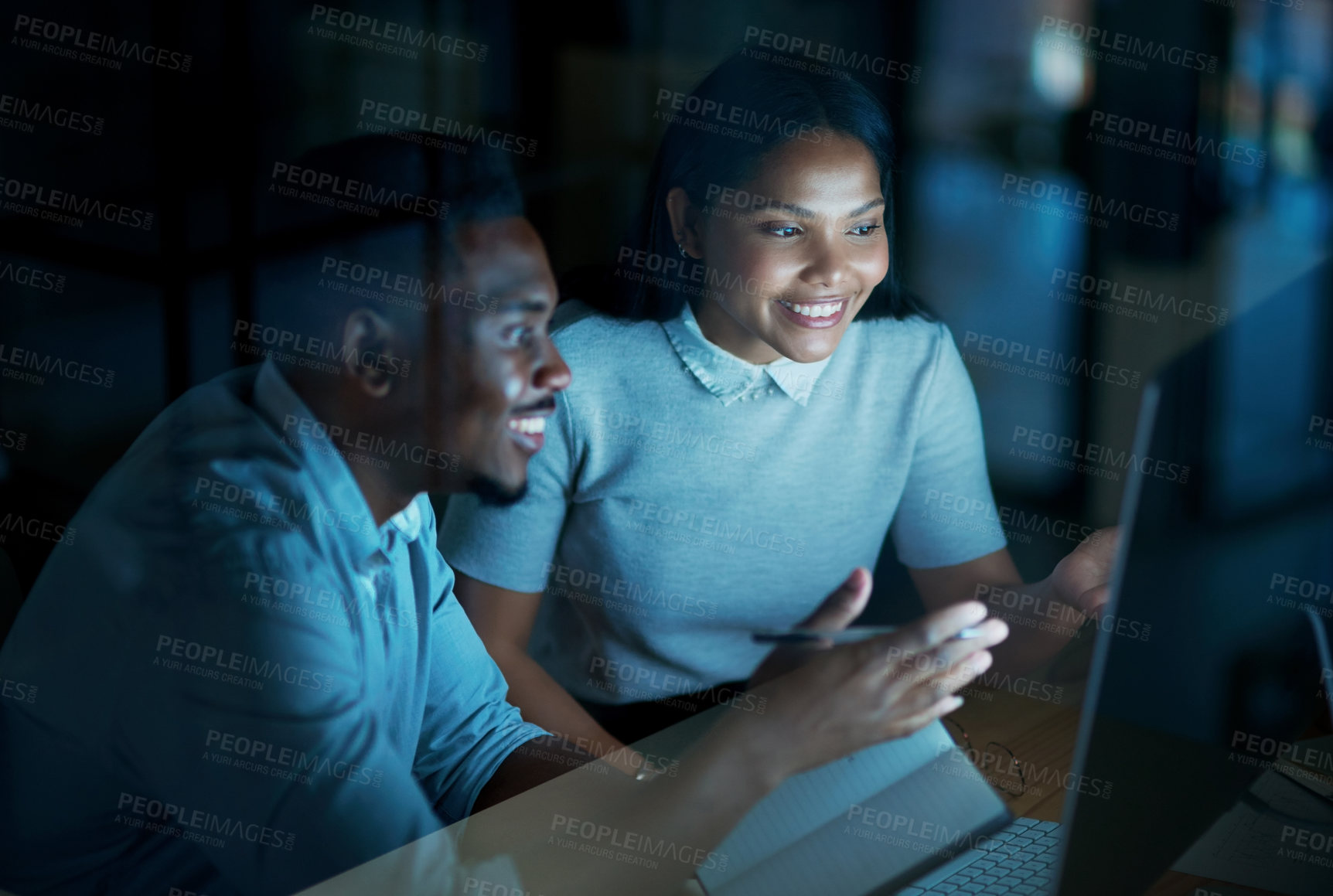 Buy stock photo Shot of a young businesswoman and businessman using a computer together during a late night at work