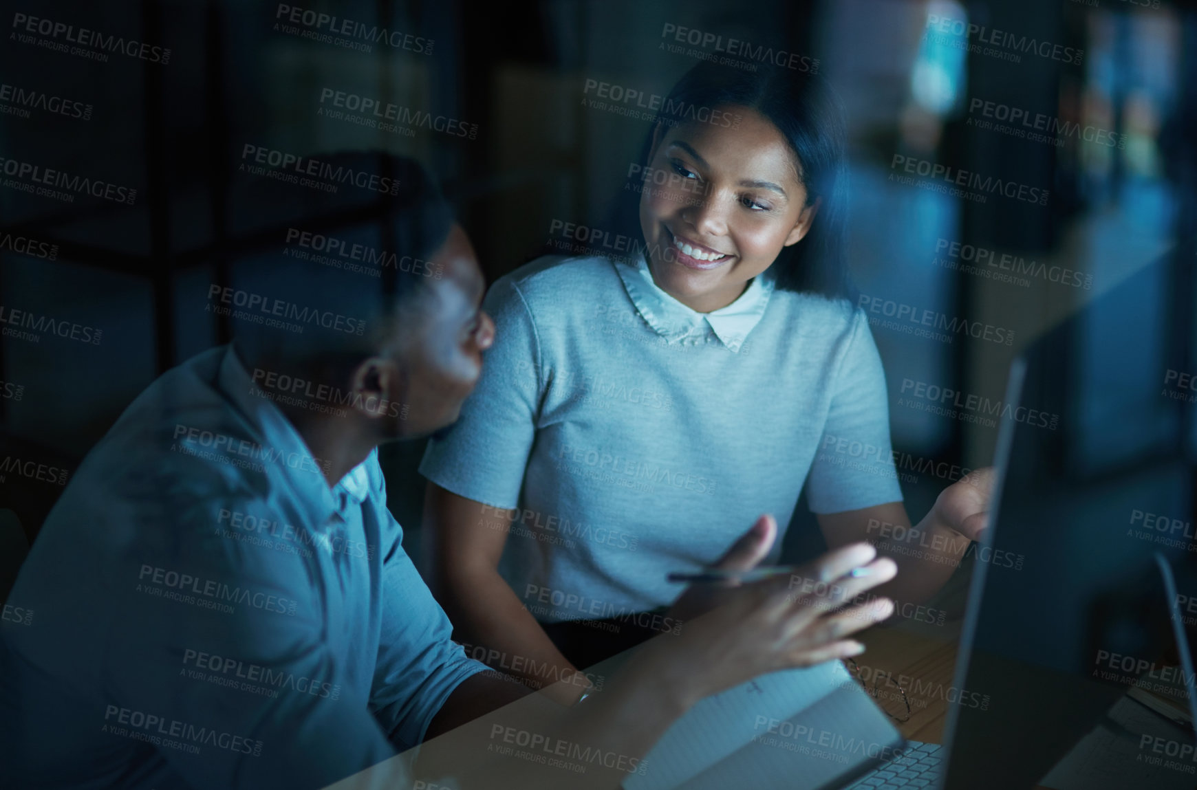 Buy stock photo Shot of a young businesswoman and businessman using a computer together during a late night at work