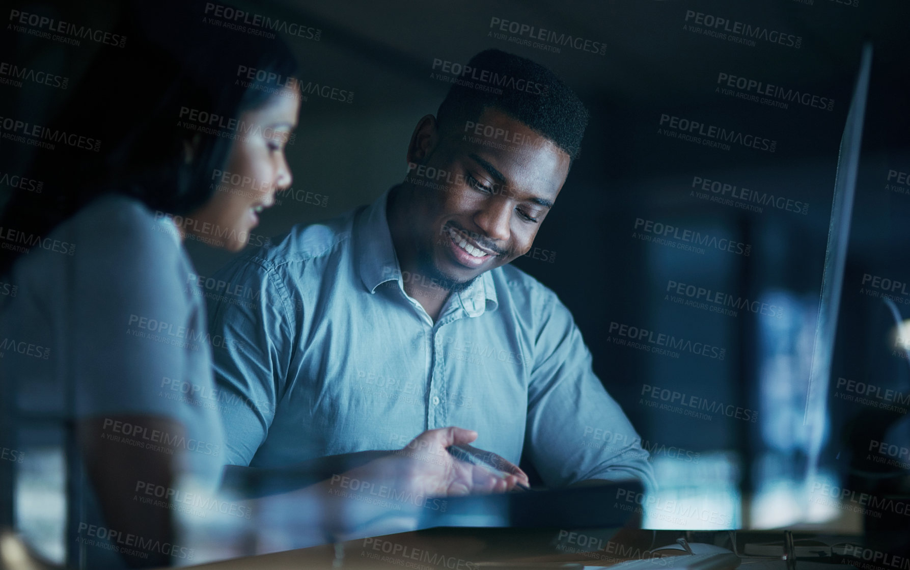 Buy stock photo Shot of a young businesswoman and businessman using a computer together during a late night at work