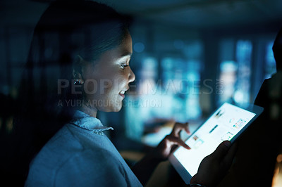 Buy stock photo Shot of a young businesswoman using a digital tablet during a late night at work