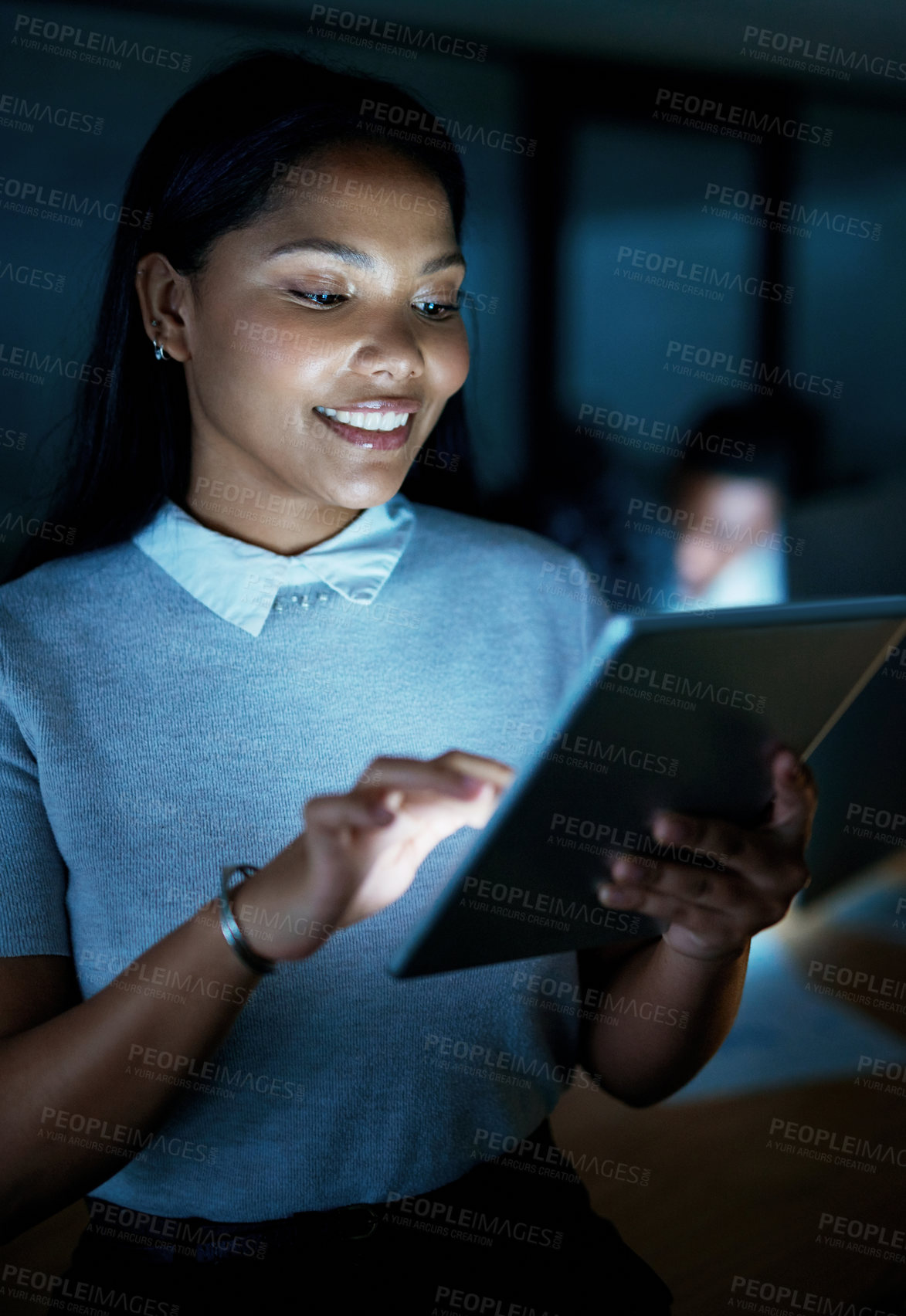 Buy stock photo Shot of a young businesswoman using a digital tablet during a late night at work