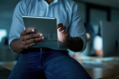 Buy stock photo Shot of an unrecognisable businessman using a digital tablet during a late night at work