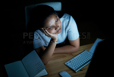 Buy stock photo Shot of a young businesswoman looking bored while using a computer during a late night at work