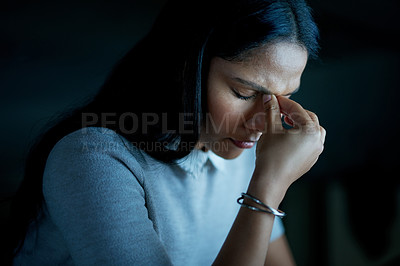 Buy stock photo Shot of a young businesswoman looking stressed during a late night at work