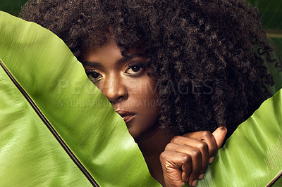 Buy stock photo Shot of a beautiful young woman covering herself with a plant