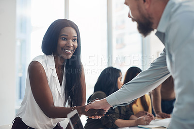 Buy stock photo Cropped shot of two young businesspeople shaking hands during a meeting in the office