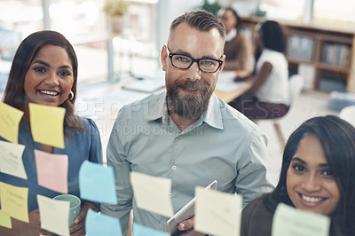 Buy stock photo Cropped portrait of a diverse group of businesspeople standing together and using a glass board to brainstorm in the office