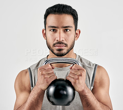 Buy stock photo Studio portrait of a muscular young man exercising with a kettlebell against a white background