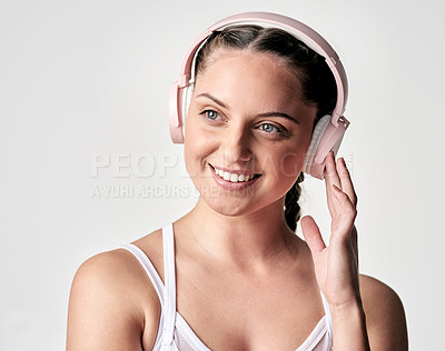 Buy stock photo Studio shot of a sporty young woman wearing headphones against a white background