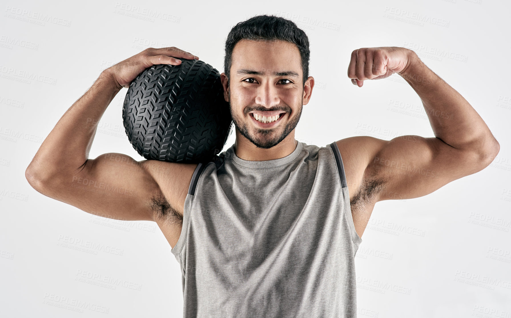 Buy stock photo Studio portrait of a muscular young man flexing while holding an exercise ball against a white background