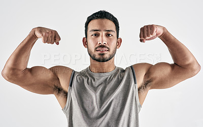 Buy stock photo Studio portrait of a muscular young man flexing his biceps against a white background