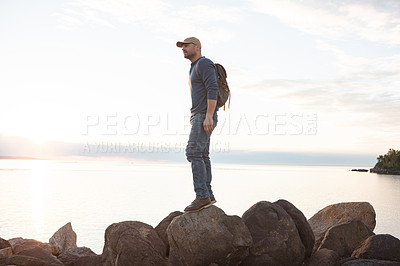 Buy stock photo Shot of a man wearing his backpack while out for a hike on a coastal trail