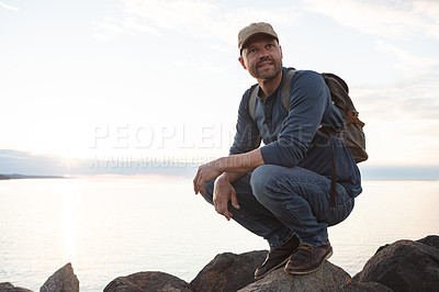 Buy stock photo Shot of a man wearing his backpack while out for a hike on a coastal trail