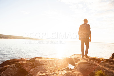 Buy stock photo Shot of a man wearing his backpack while out for a hike on a coastal trail