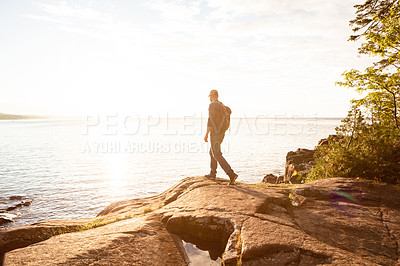 Buy stock photo Shot of a man wearing his backpack while out for a hike on a coastal trail