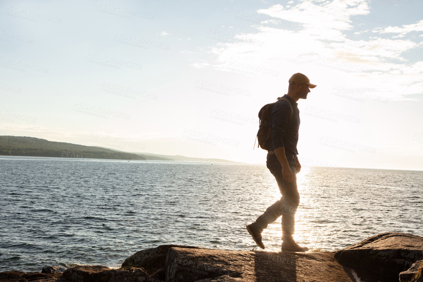 Buy stock photo Shot of a man wearing his backpack while out for a hike on a coastal trail