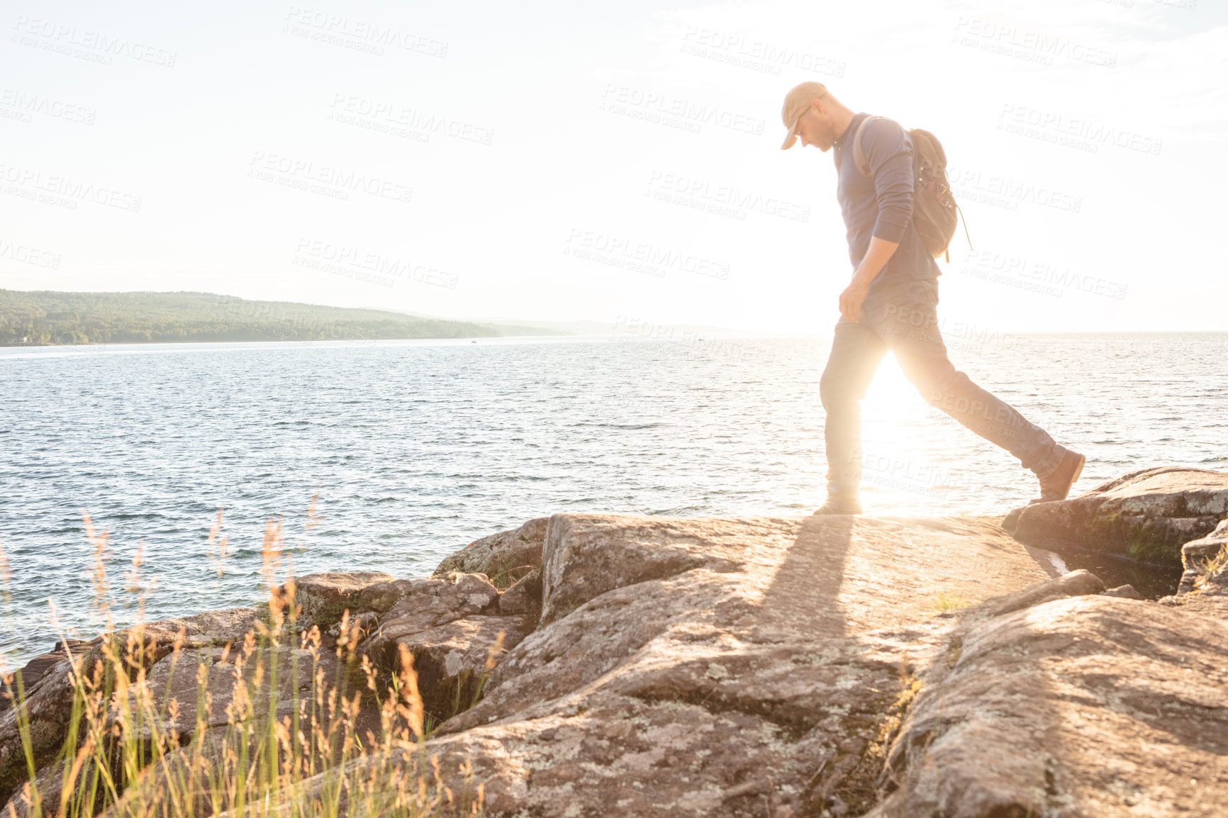 Buy stock photo Shot of a man wearing his backpack while out for a hike on a coastal trail