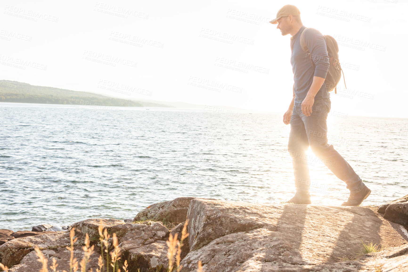 Buy stock photo Shot of a man wearing his backpack while out for a hike on a coastal trail