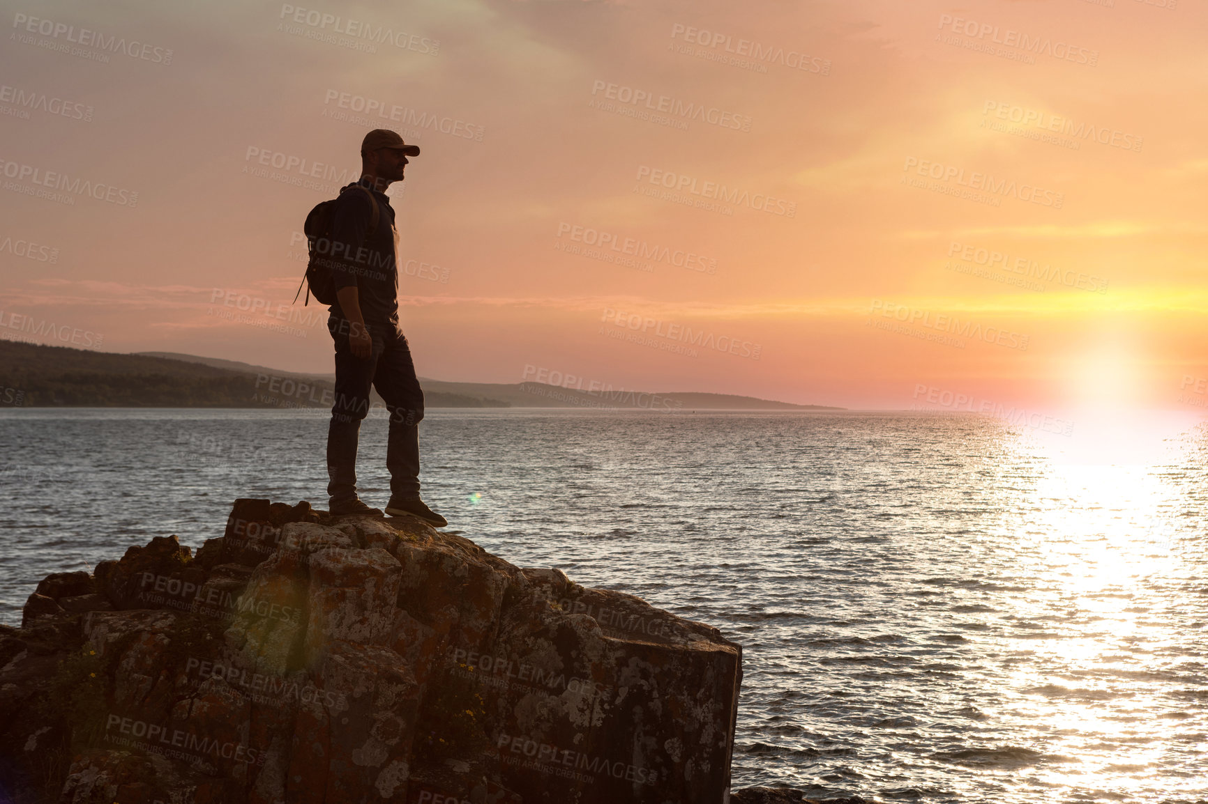 Buy stock photo Shot of a man wearing his backpack while out for a hike on a coastal trail