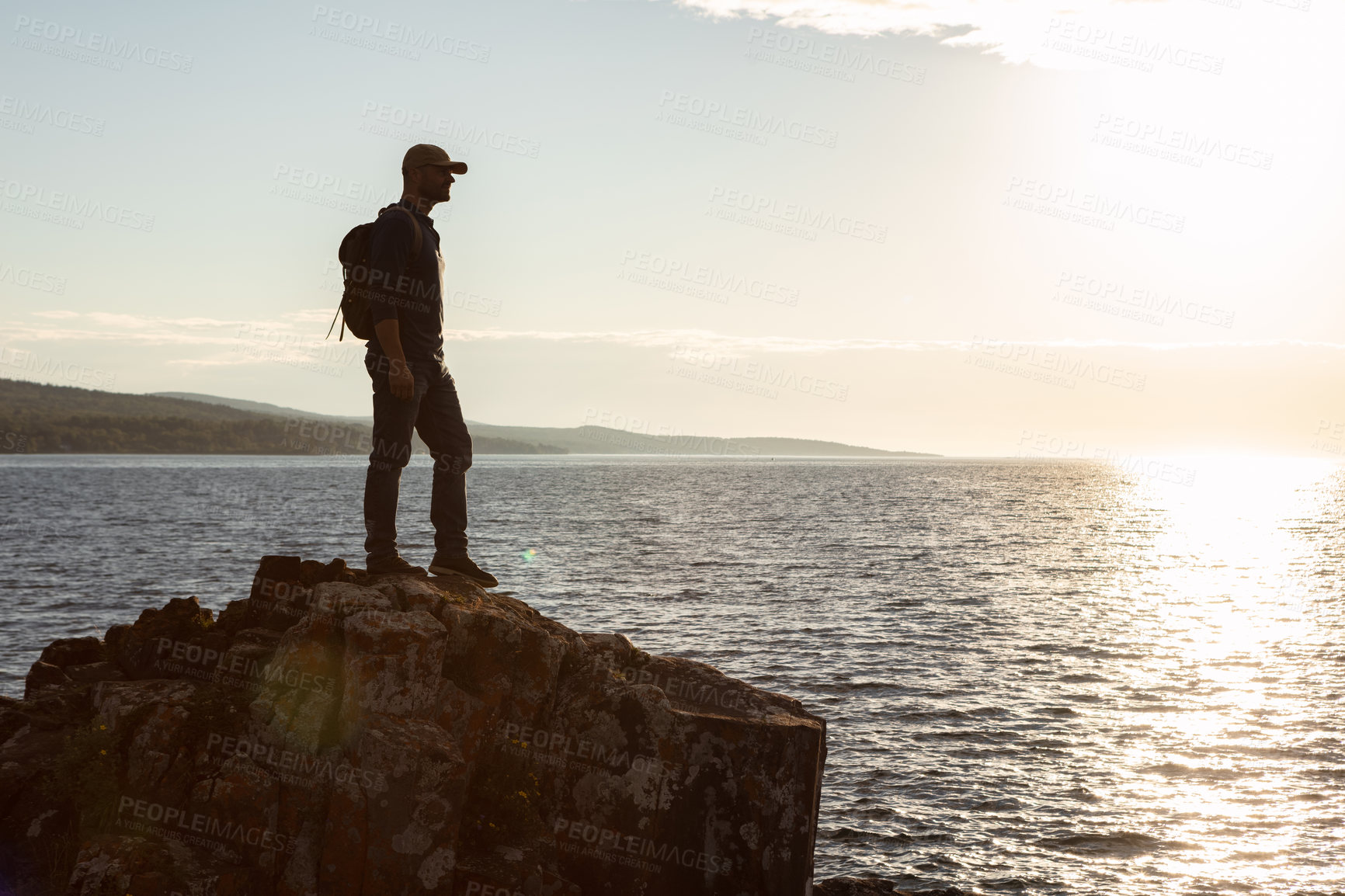 Buy stock photo Shot of a man wearing his backpack while out for a hike on a coastal trail