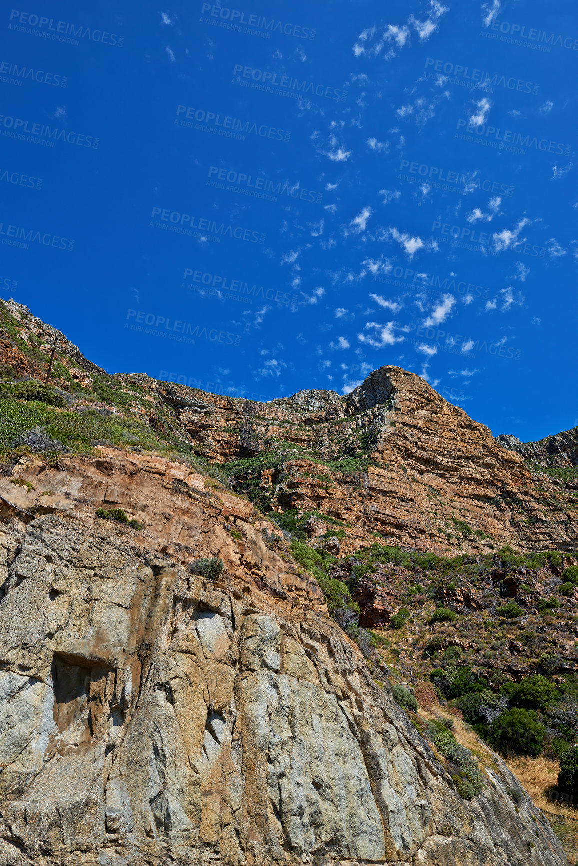 Buy stock photo Scenic landscape of mountains against a blue sky background with scattered clouds and copy space from below. Wild plants and shrubs growing on rocky hill and cliff in a remote and natural environment