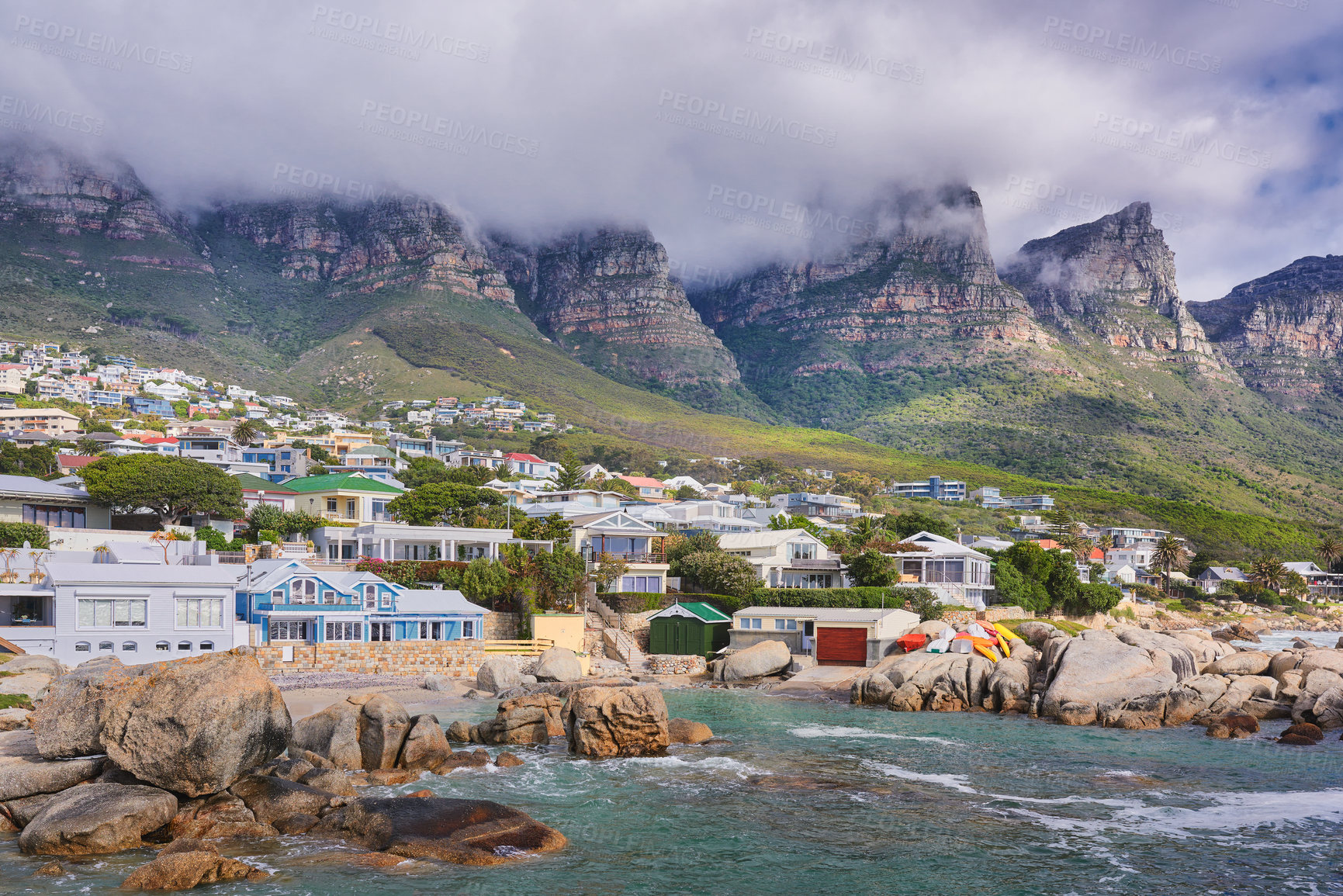 Buy stock photo Landscape view of a seaside town along the mountain on a cloudy day in Cape Town, South Africa. Scenic view of a quiet and secluded residential area on the coast for tourists and holidays in summer