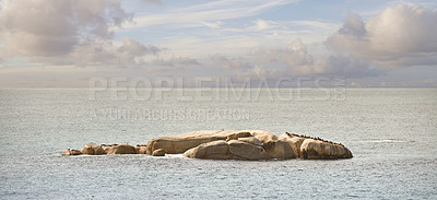 Buy stock photo Ocean view in Camps Bay,  Cape Town in South Africa. Beautiful landscape view of a boulder or rock in the middle of the sea against a cloudy blue sky in summer. Beach and coast scenery during the day