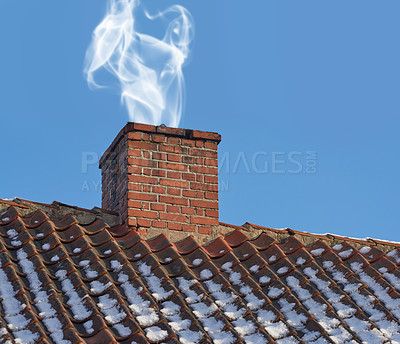 Buy stock photo Landscape of chimney blowing smoke on house rooftop exterior design in Denmark during winter. Close up of old architecture redbrick air vent for removing heat and smoke from fireplace with blue sky