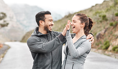 Buy stock photo Shot of a sporty young man and woman giving each other a high five outdoors