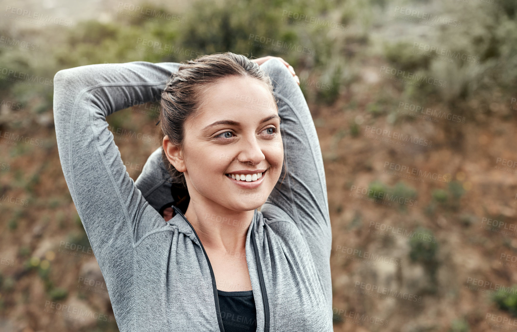 Buy stock photo Shot of a sporty young woman stretching her arms while exercising outdoors