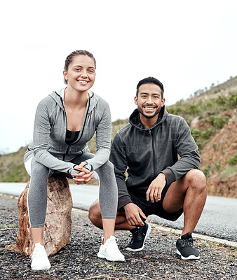 Buy stock photo Portrait of a sporty young man and woman taking a break while exercising outdoors