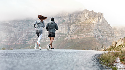 Buy stock photo Rearview shot of a sporty young man and woman running together outdoors