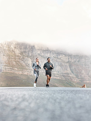 Buy stock photo Shot of a sporty young man and woman running together outdoors